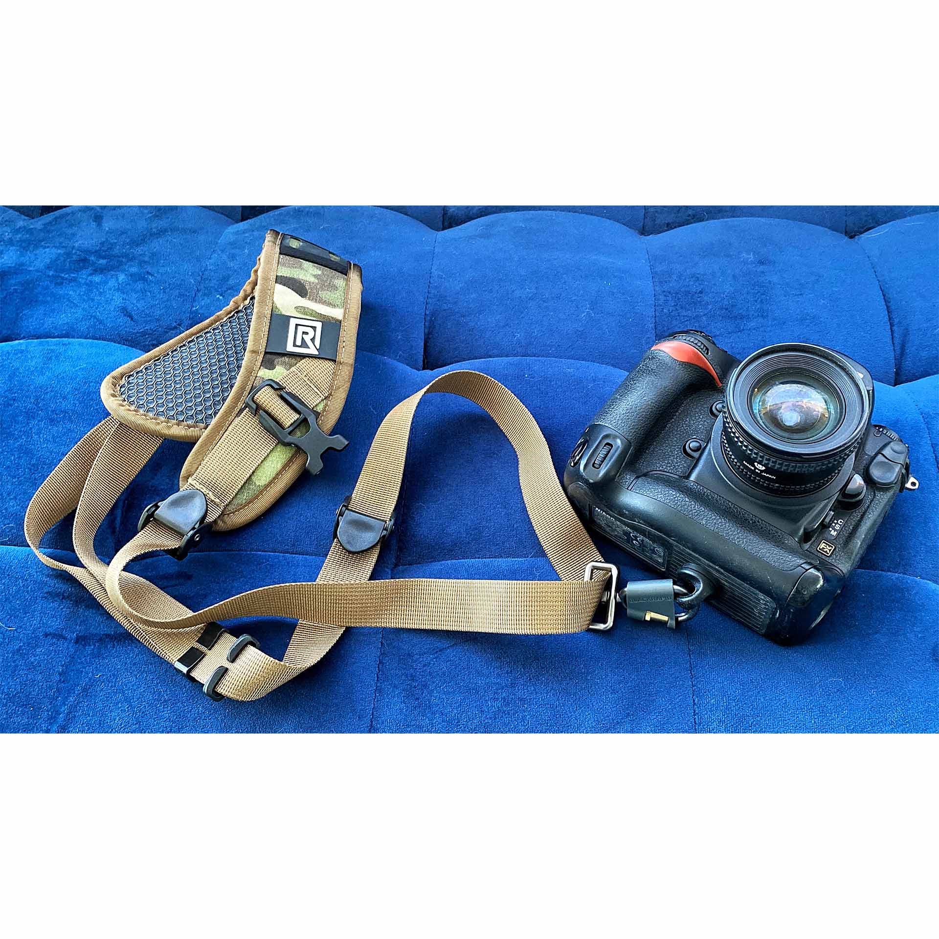 291008-SPORT-X-4 - BLACKRAPID Canada Camera strap and camera resting on a blue couch, showcasing the Sport X camera sling in a stylish setting.