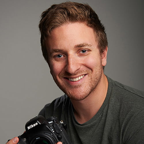 A man smiling while holding a camera, ready to capture a moment.