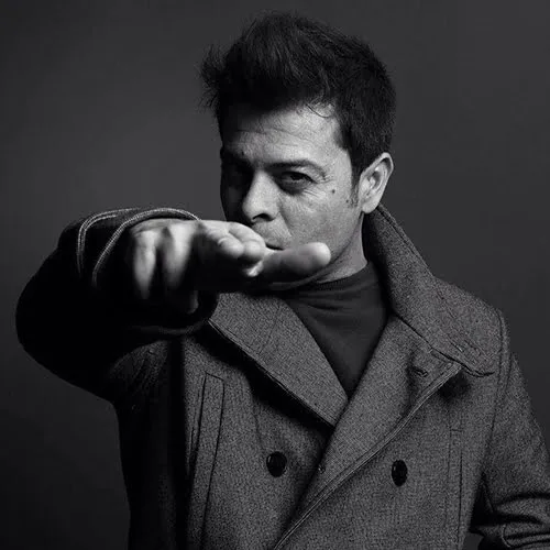 A man in a coat is pointing at an object or direction, indicating interest or instruction.