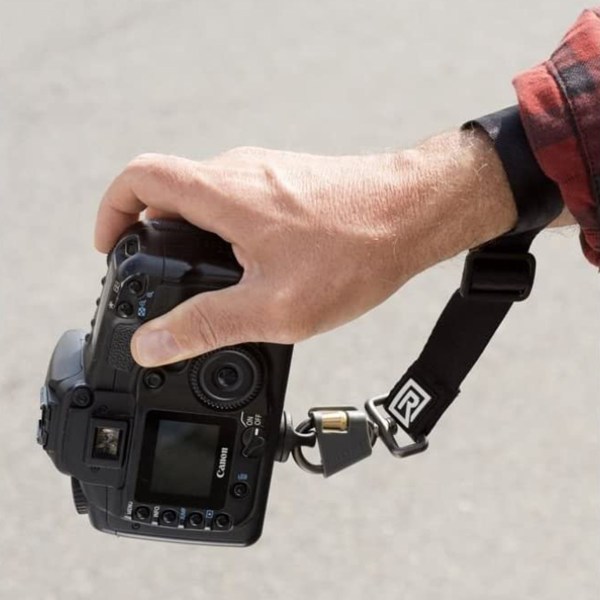 Close-up of BlackRapid Wrist Breathe strap worn on hand, attached to camera.