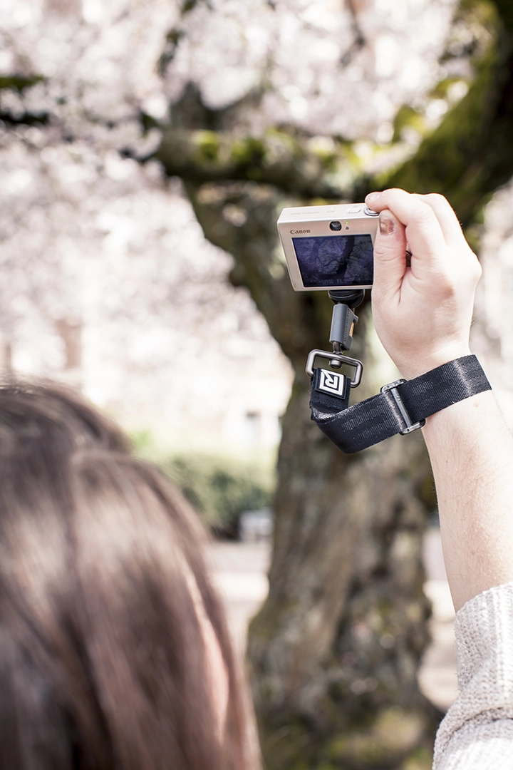 A person holding a camera with a blackrapid wrist strap, ready to take a photo, showcasing their enthusiasm for photography.