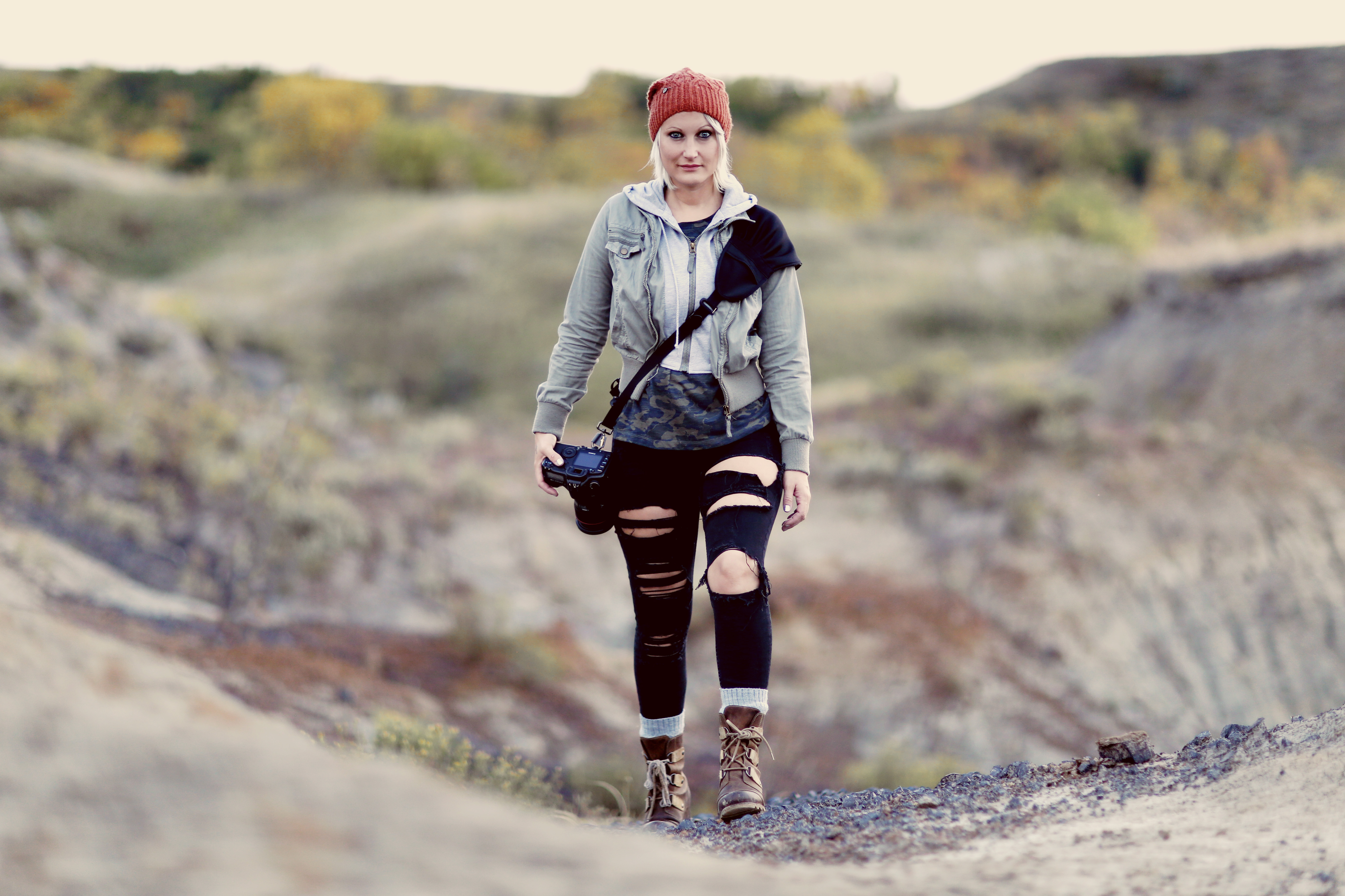 a photographer standing in a mountain alone with her camera and blackrapid strap